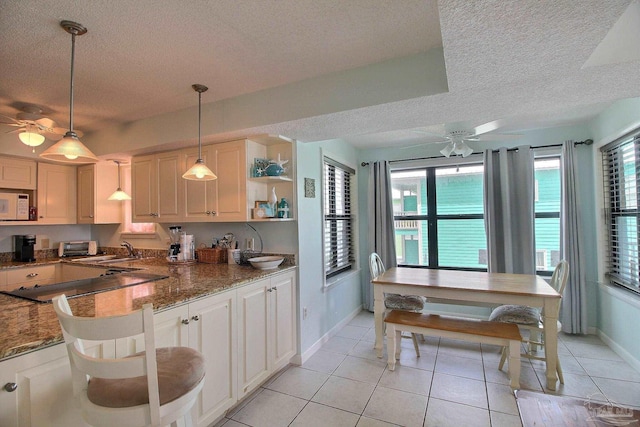 kitchen featuring decorative light fixtures, white cabinets, dark stone counters, ceiling fan, and black cooktop