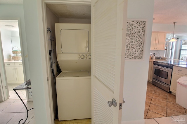 washroom featuring stacked washing maching and dryer and light tile patterned flooring