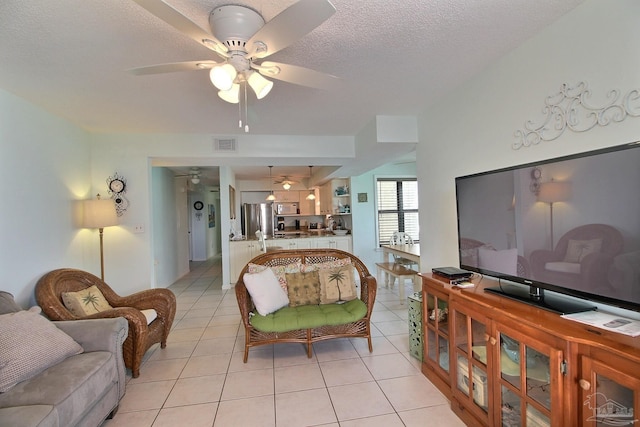 tiled living room featuring ceiling fan and a textured ceiling