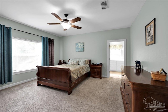 bedroom with light carpet, ensuite bathroom, and ceiling fan