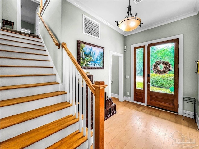 entryway with ornamental molding and light hardwood / wood-style floors