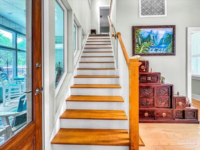 stairway featuring a healthy amount of sunlight and hardwood / wood-style flooring