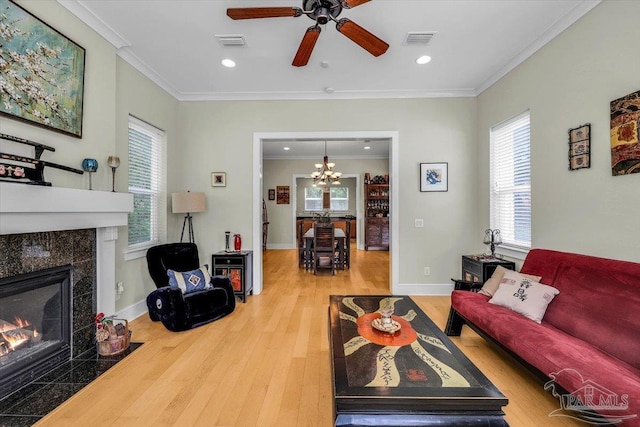 living room with a tile fireplace, plenty of natural light, crown molding, and hardwood / wood-style floors