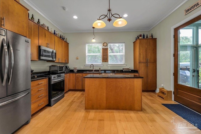 kitchen featuring sink, a kitchen island, decorative light fixtures, stainless steel appliances, and ornamental molding