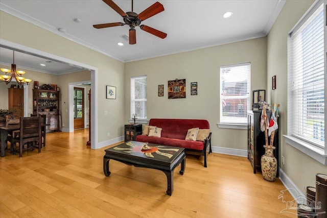 living room with ceiling fan with notable chandelier, light wood-type flooring, plenty of natural light, and ornamental molding