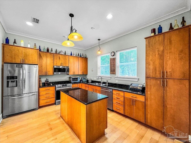 kitchen with appliances with stainless steel finishes, sink, a center island, crown molding, and hanging light fixtures