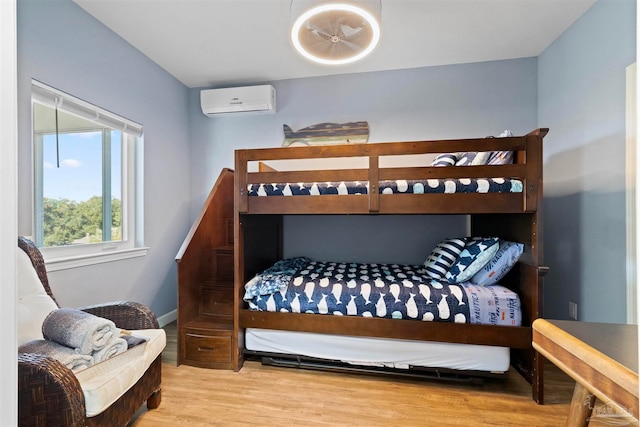 bedroom with hardwood / wood-style floors and a wall mounted air conditioner