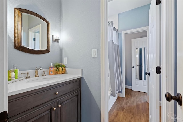 bathroom featuring wood-type flooring, vanity, and shower / tub combo with curtain