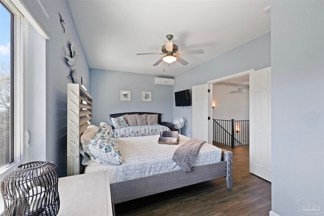 bedroom featuring multiple windows, dark hardwood / wood-style floors, ceiling fan, and a wall mounted air conditioner