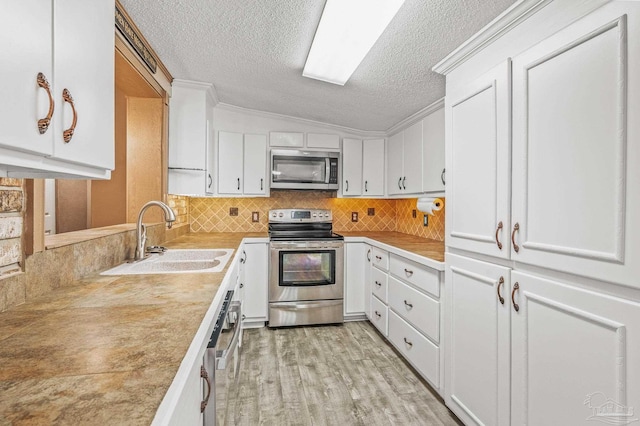 2931 Pine Forest Rd, Cantonment, FL 32533 - kitchen with stainless steel appliances, a sink, lofted ceiling, a textured ceiling, and white cabinetry