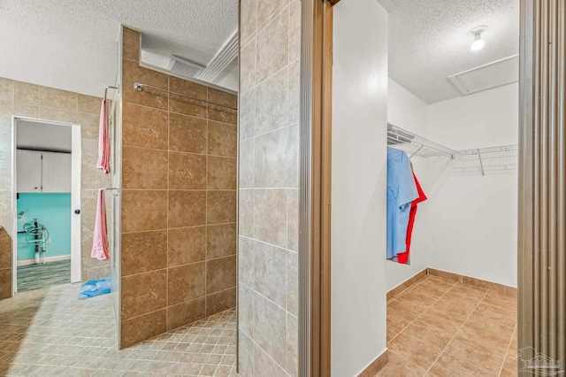 2931 Pine Forest Rd, Cantonment, FL 32533 - bathroom featuring a textured ceiling, walk in shower, tile patterned flooring, and a spacious closet