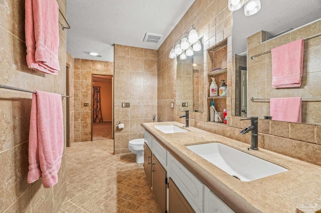 2931 Pine Forest Rd, Cantonment, FL 32533 - bathroom featuring tile walls, a textured ceiling, toilet, double vanity, and tile patterned flooring