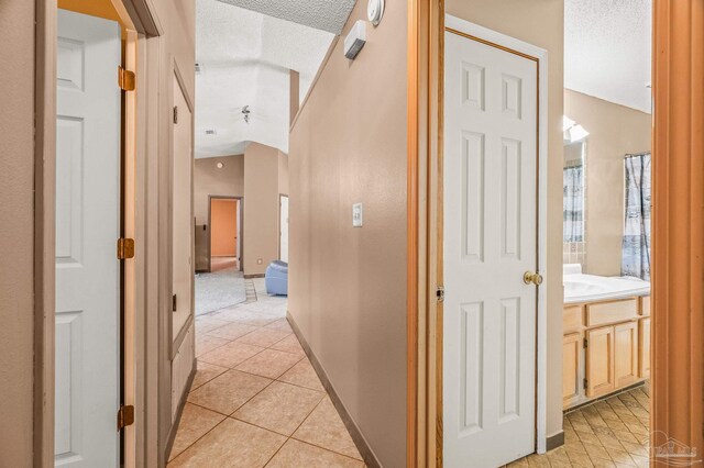 2931 Pine Forest Rd, Cantonment, FL 32533 - corridor with a textured ceiling, light tile patterned floors, vaulted ceiling, and baseboards