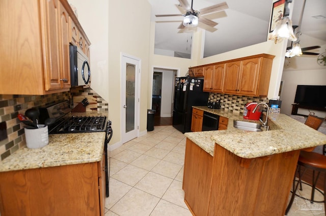 kitchen featuring a kitchen breakfast bar, decorative backsplash, kitchen peninsula, black appliances, and sink