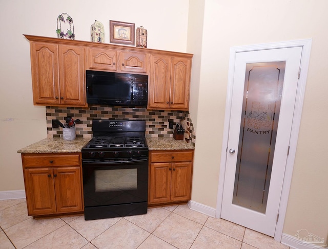 kitchen with light stone countertops, black appliances, light tile patterned flooring, and backsplash