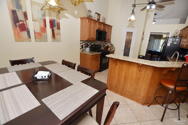 dining area with ceiling fan, light tile patterned flooring, and a towering ceiling