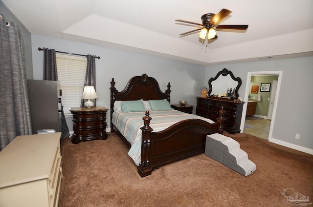 bedroom with carpet, ceiling fan, ensuite bathroom, and a raised ceiling