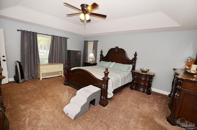 carpeted bedroom featuring a tray ceiling and ceiling fan