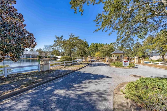 view of street with a water view, a gate, a gated entry, and curbs