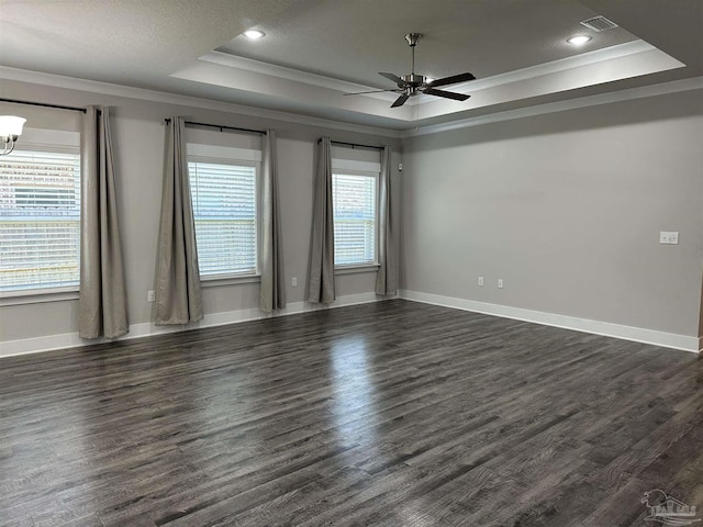 empty room featuring a raised ceiling, dark hardwood / wood-style floors, ceiling fan with notable chandelier, and crown molding