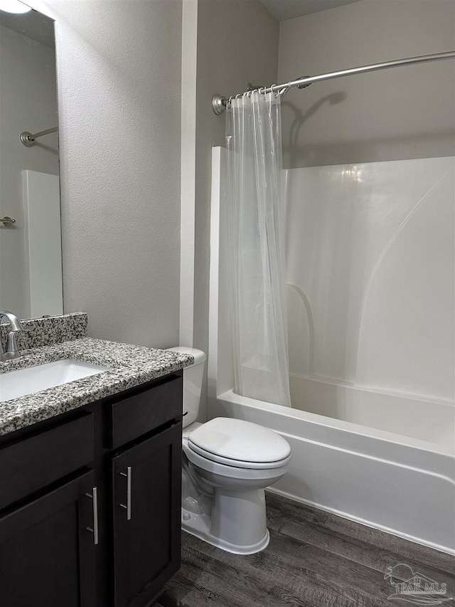 full bathroom featuring shower / bath combo with shower curtain, hardwood / wood-style flooring, vanity, and toilet