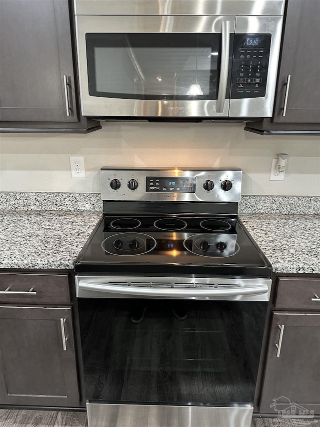 kitchen with light stone counters, stainless steel appliances, and dark brown cabinetry