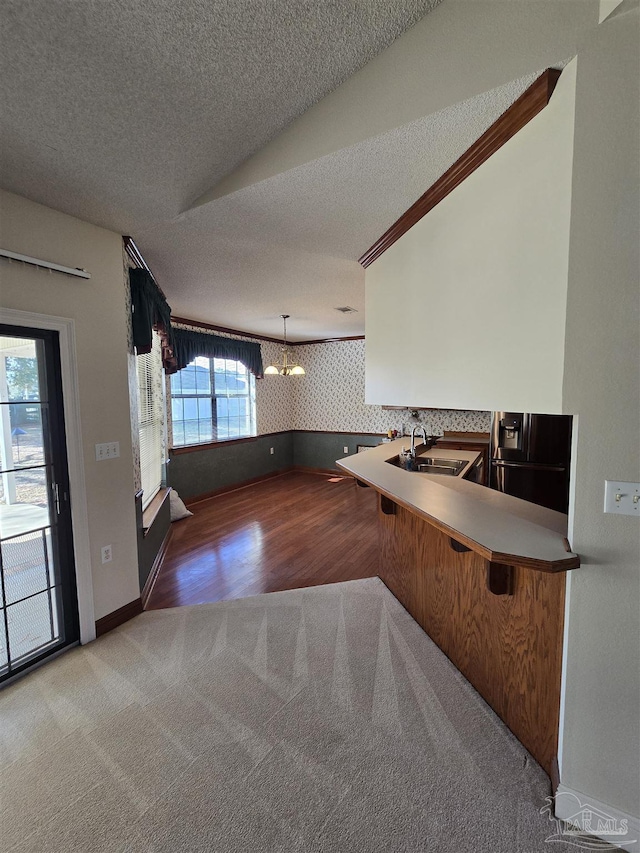 kitchen featuring sink, decorative light fixtures, a chandelier, a textured ceiling, and kitchen peninsula