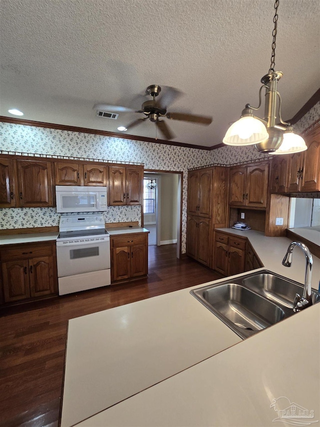 kitchen with pendant lighting, white appliances, dark hardwood / wood-style floors, and sink