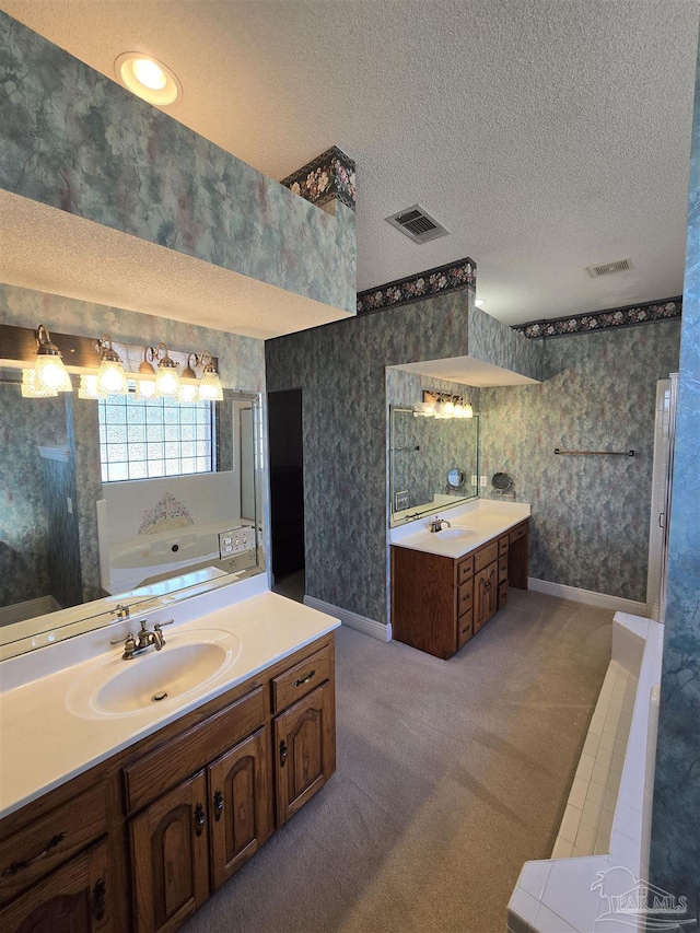 bathroom featuring vanity, a bath, and a textured ceiling