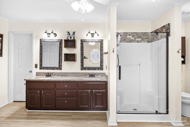 bathroom featuring a stall shower, ornamental molding, a sink, and wood finished floors