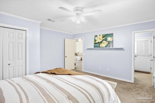 carpeted bedroom with baseboards, visible vents, a textured ceiling, crown molding, and a closet