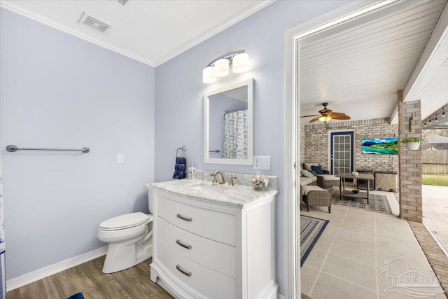 bathroom with toilet, brick wall, ornamental molding, wood finished floors, and vanity