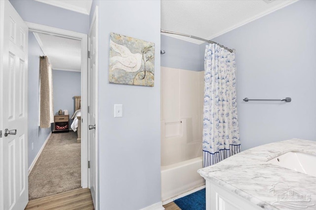 bathroom with vanity, ornamental molding, wood finished floors, shower / bath combination with curtain, and a textured ceiling