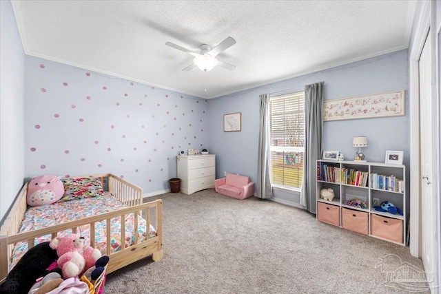 carpeted bedroom featuring baseboards, a ceiling fan, a textured ceiling, and ornamental molding