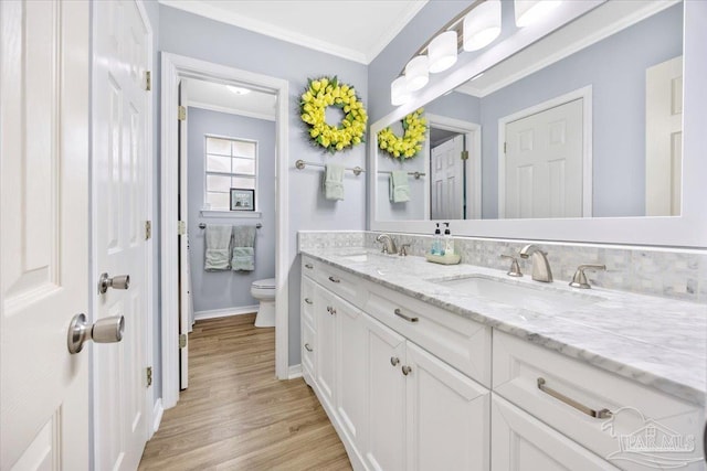 full bath with crown molding, double vanity, toilet, a sink, and wood finished floors