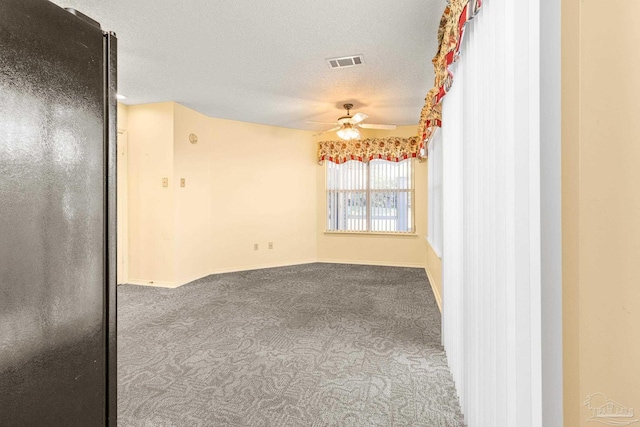 spare room with a textured ceiling, carpet flooring, and ceiling fan