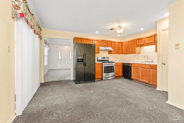 kitchen with black appliances, a textured ceiling, dark carpet, and sink