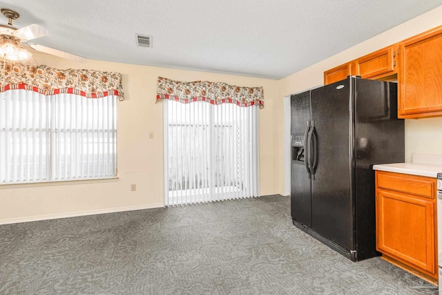 kitchen with a textured ceiling, ceiling fan, carpet floors, and black refrigerator with ice dispenser