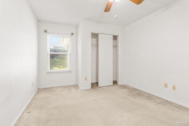 unfurnished bedroom featuring a closet, light colored carpet, and ceiling fan