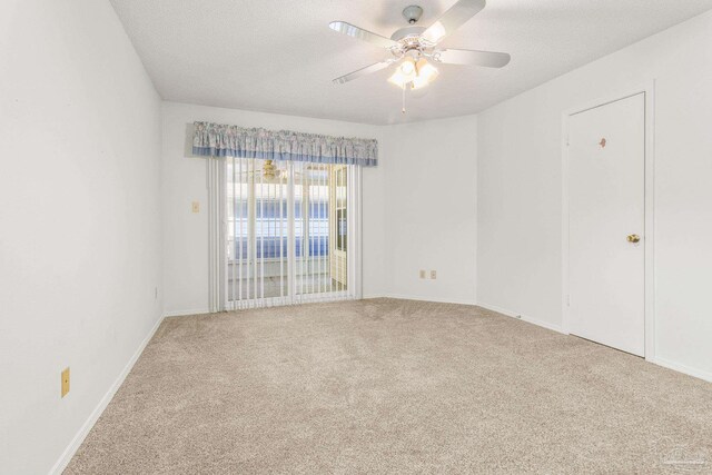 spare room featuring a textured ceiling, light colored carpet, and ceiling fan