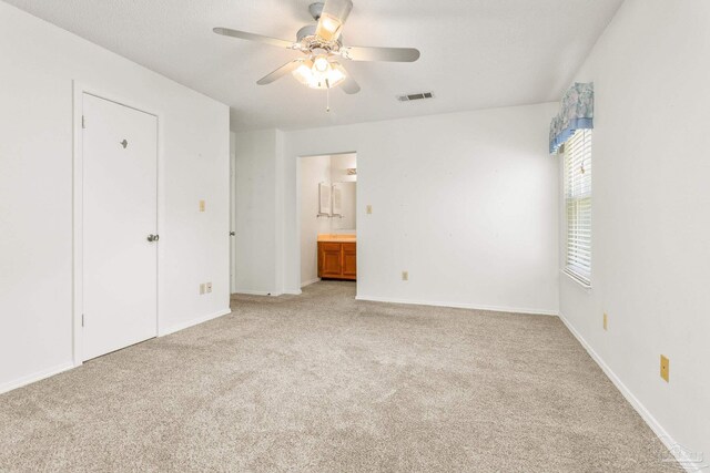 unfurnished bedroom featuring ceiling fan, light carpet, and ensuite bathroom