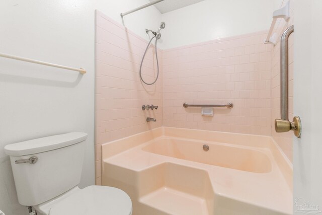 bathroom with toilet and tiled shower / bath