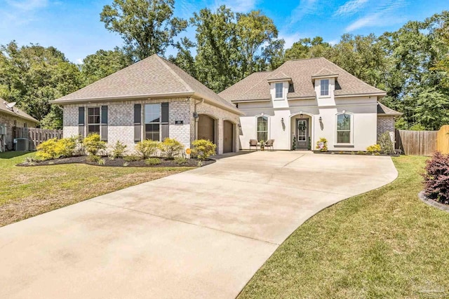2120 Eagles Ridge Cv, Cantonment, FL 32533 - french country inspired facade with an attached garage, concrete driveway, brick siding, central AC unit, and roof with shingles