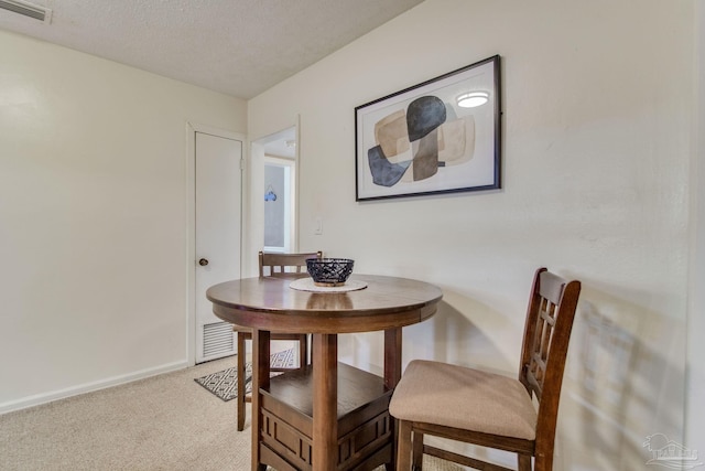 carpeted dining space featuring a textured ceiling