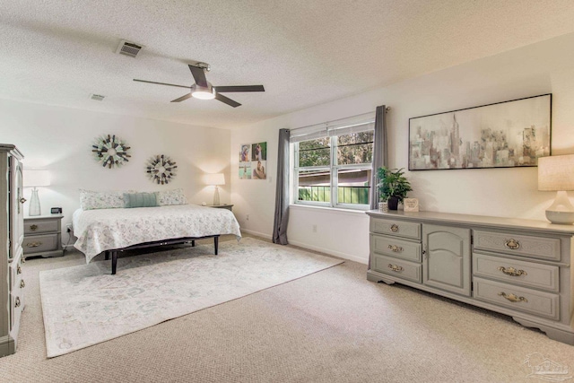 carpeted bedroom featuring ceiling fan and a textured ceiling