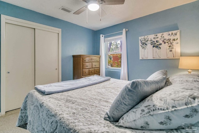 bedroom with light colored carpet, ceiling fan, and a closet