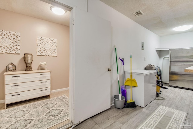 laundry area with light hardwood / wood-style flooring and a textured ceiling