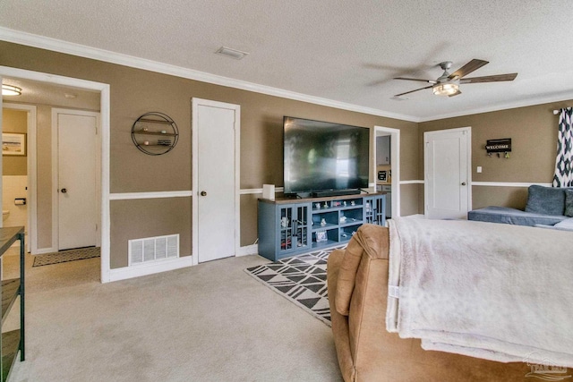 living room with ceiling fan, ornamental molding, carpet flooring, and a textured ceiling