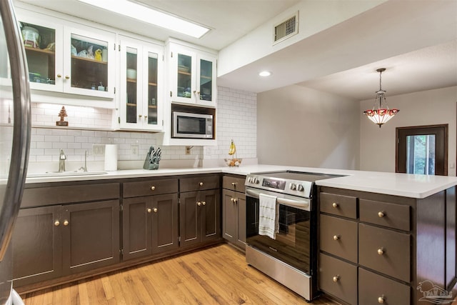 kitchen with tasteful backsplash, a peninsula, light countertops, visible vents, and stainless steel appliances