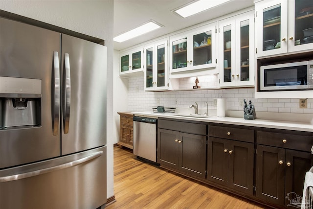kitchen featuring backsplash, light countertops, light wood finished floors, and stainless steel appliances